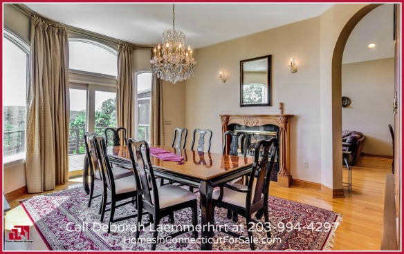 The elegant formal dining room in this waterfront home for sale in CT has walls of windows overlooking the pool and the breathtaking views.